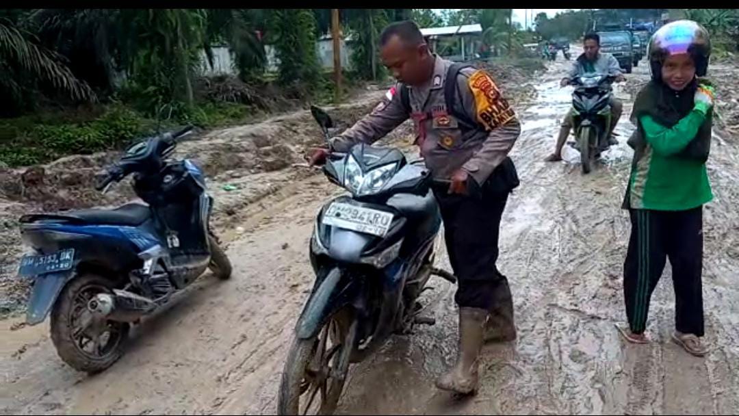 Personel Polsek Rupat Utara Bantu Warga yang Melintasi Jalan Poros Desa Kadur