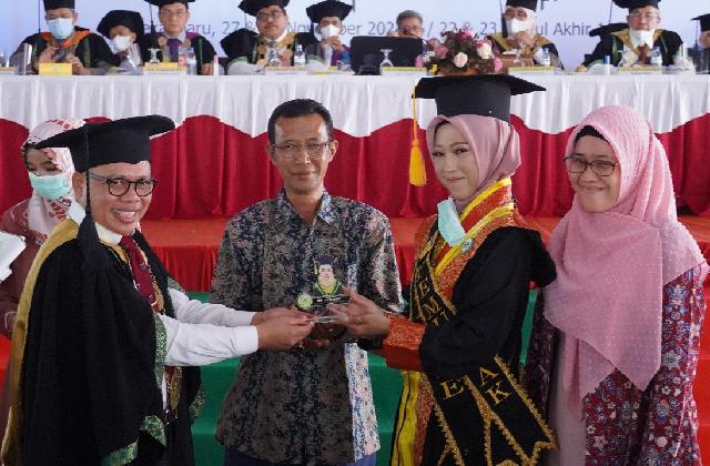 Penyerahan cinderamata dari Rektor Universitas Muhammadiyah Riau (UMRI), DR. Mubarak, M.Si kepada seorang wisudawati dalam prosesi wisuda ke XX dan XXI.